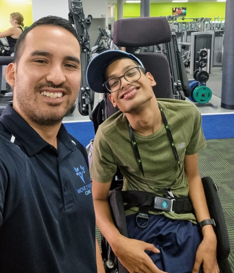 Exercise Physiologist Jeremy with NDIS participant in the gym smiling