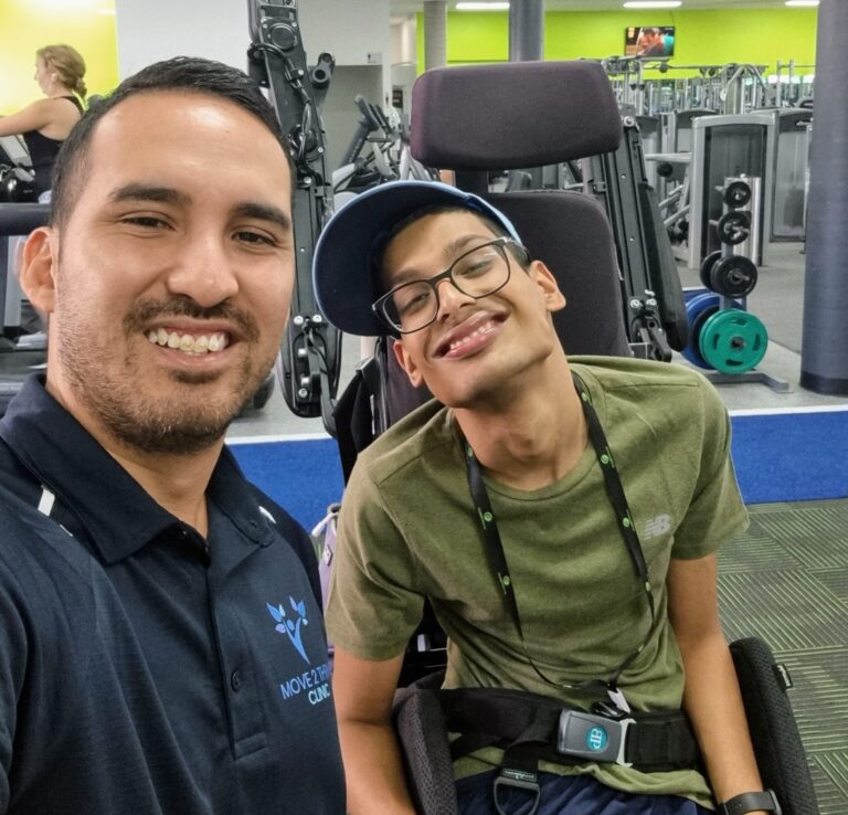 Exercise Physiologist Jeremy with NDIS participant in the gym smiling